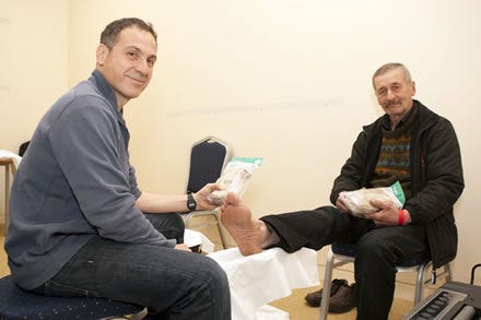 Podiatrist Jonathan Richards giving Cosyfeet socks to a Crisis at Christmas guest.