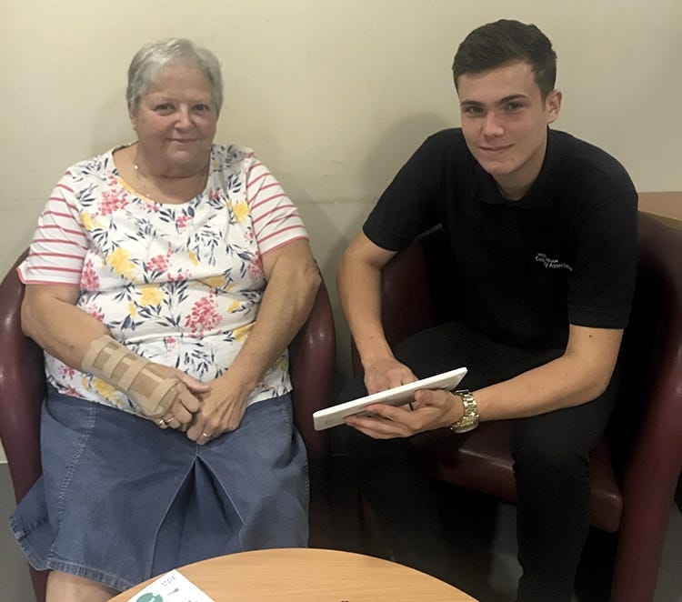 Tom (16) shows retired local resident Chris how to use a tablet