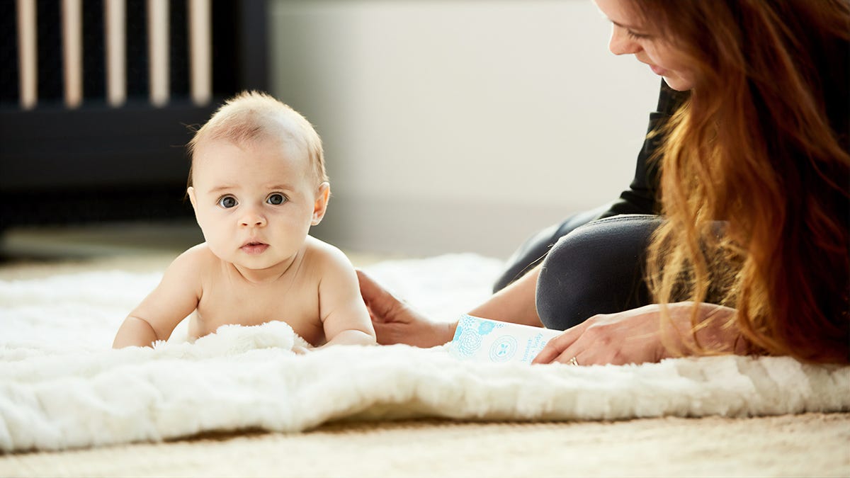 A baby laying on their stomach with their mum