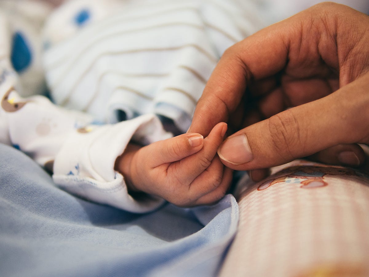 A grandparent holding a newborn baby’s hand